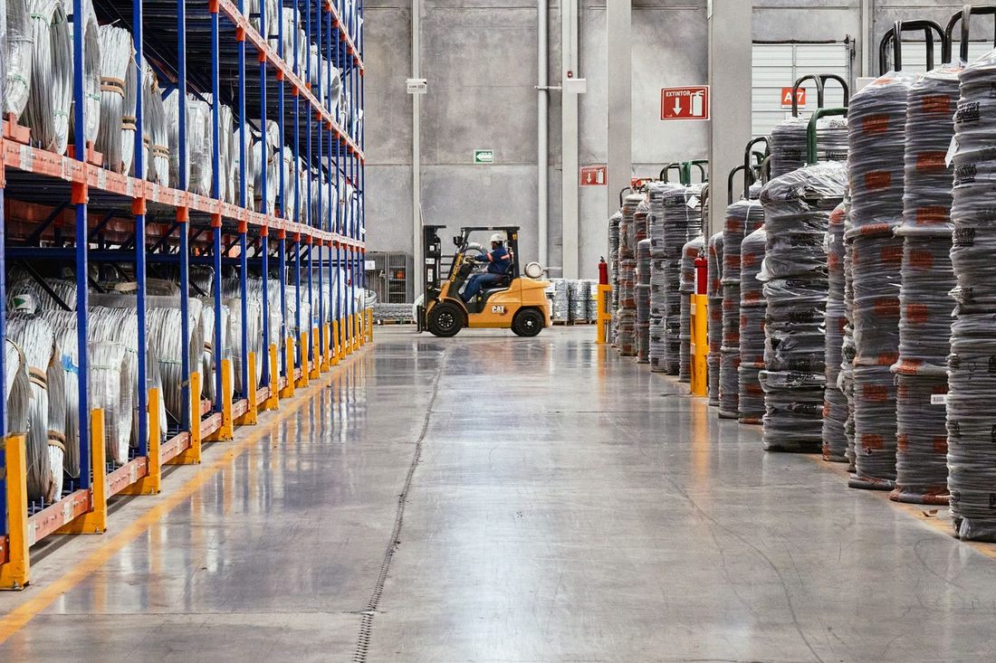 Home 12 Forklift moving palletised goods down a warehouse aisle
